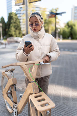 Female cyclist using cellphone on streetの写真素材
