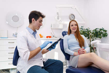 Male dentist using tablet near female patientの写真素材