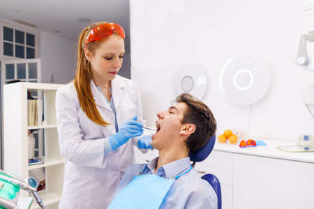 Ginger dentist examining teeth of male patientの写真素材