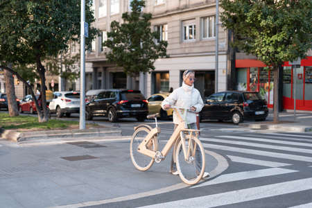 Female cyclist walking near crosswalkの写真素材