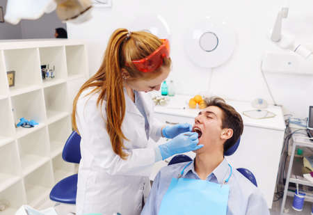 Ginger dentist examining teeth of young patientの写真素材