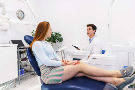 Female patient listening to male dentist in clinicの写真素材