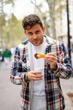 Man with churros with chocolate in streetの写真素材