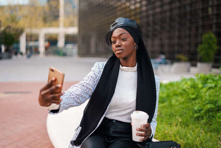 Young black woman taking selfie on smartphone in parkの写真素材