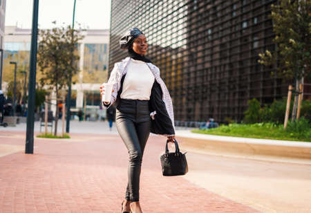 Trendy black woman with takeaway coffee rushing on workの写真素材