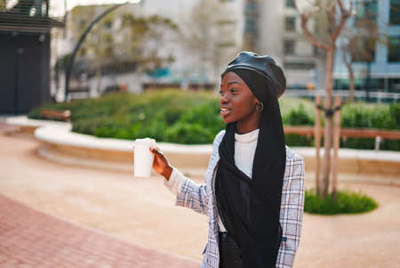 Cheerful black lady with takeaway beverage in parkの写真素材