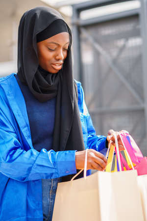 Muslim shopaholic checking purchases in paper bagsの写真素材
