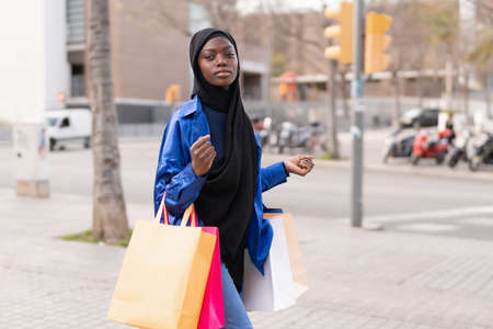Trendy Muslim shopaholic walking on streetの写真素材