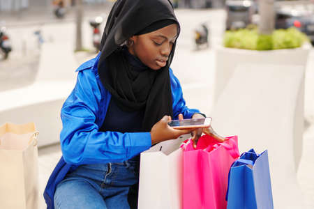 Black shopper in hijab shooting purchasesの写真素材