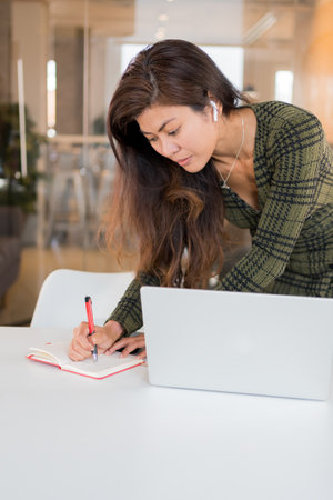 Modern female writing in planner in workspaceの写真素材