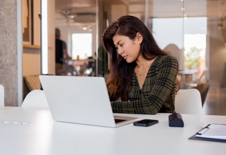 Focused woman working on laptop in officeの写真素材
