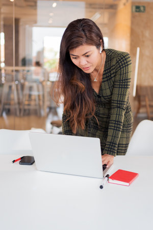 Focused woman browsing laptop at deskの写真素材