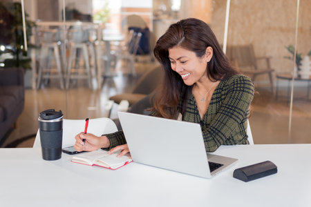 Cheerful female office worker writing in plannerの写真素材