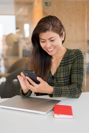 Cheerful businesswoman with phone at deskの写真素材