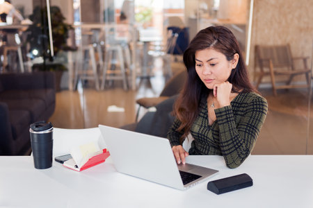 Focused lady with laptop working in officeの写真素材