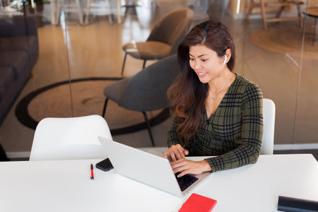Smiling woman typing on laptop in officeの写真素材