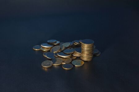 Banking and money trading. Golden metal coins stacked in different combinations on dark blue blurred background. Serbian metal coin, copy spaceの写真素材