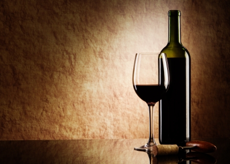 green bottle with red wine and glass and cork with a corkscrew on a old stone green bottle with red wine and glass and cork with a corkscrew on a old stone