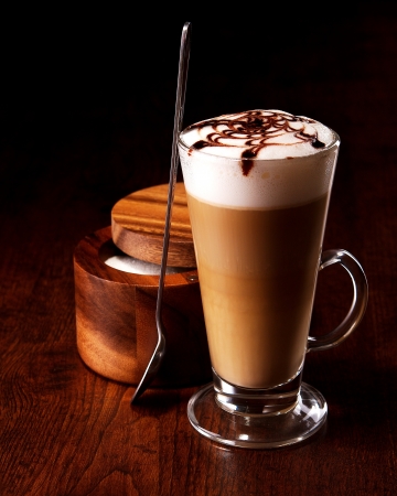 latte mug on a wooden table with a spoon and sugarの写真素材