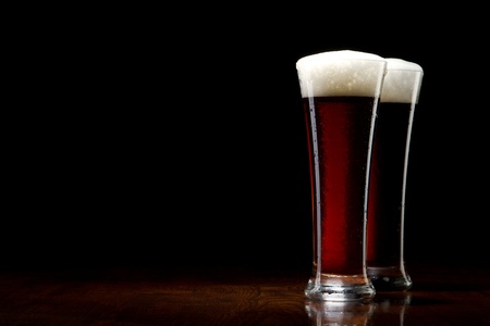 two Beer into glass on a black and wooden tableの写真素材