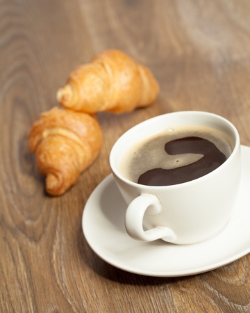 Breakfast with coffee and croissants in a basket on tableの写真素材