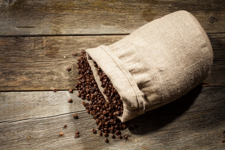 Burlap sack of coffee beans against dark wood backgroundの写真素材