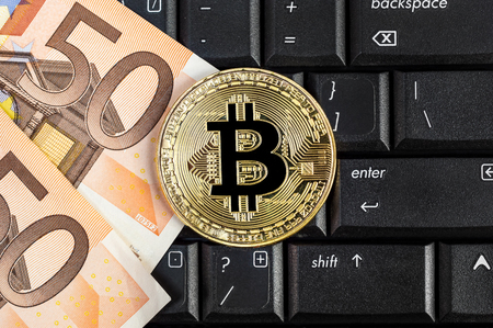 Golden bitcoin with euro bills on laptop keyboard. E-commerce concept.の写真素材