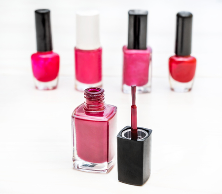 Opened bottle of nail polish with brushes on the white wooden table.の写真素材