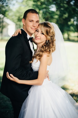 Elegant bride and groom posing together outdoors on a wedding day in the parkの写真素材