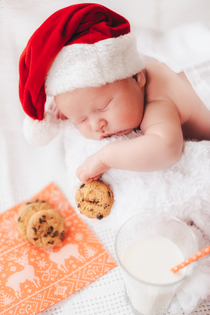 Child sleeps in a hat of Santa Claus on a white blanketの写真素材