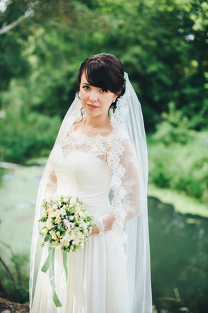 close-up bride in white dress with wedding bouquet at the lakeの写真素材