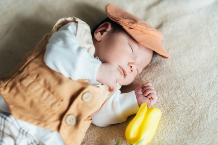 Cute child baby boy with yellow tulips in a waistcoat and a cap. Mothers day, spring concept.の写真素材