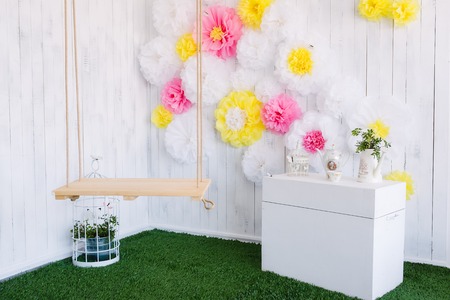 Photo zone in the studio with paper flowers, swings and grass