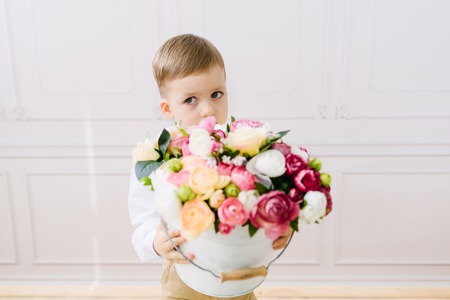 Boy holding a bucket of flowers on a white background in studio