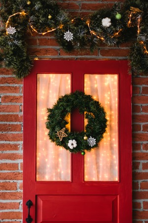 Christmas wreath on red door with garlandsの写真素材