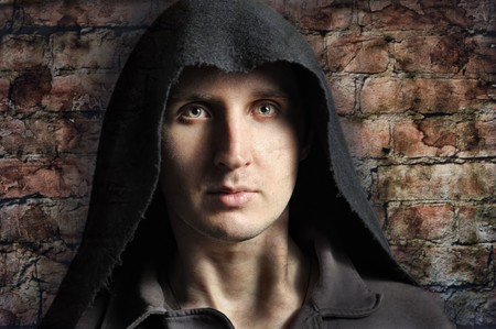 Spooky man in hood with brick wall on backgroundの写真素材