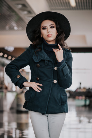 Fashionable girl in coat with hat indoorsの写真素材