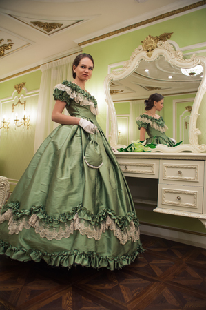 Portrait of retro baroque fashion woman wearing green vintage dress at old palace interiorの写真素材