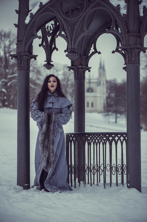 Fairytale of young woman dressed in long sleeved coat at winter with snow outdoorsの写真素材