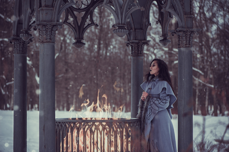 Fairytale of young woman dressed in long sleeved coat at winter with snow outdoorsの写真素材