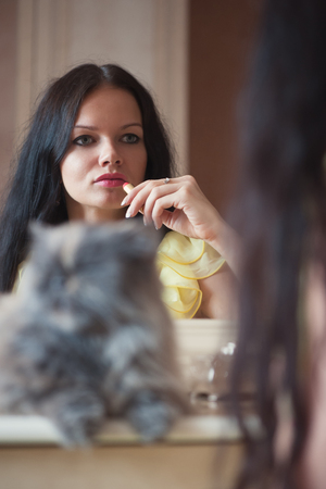 Portrait of woman with cat in yellow dress indoors near mirrorの写真素材