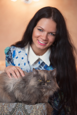 Pretty young woman with her cat lying on the bedの写真素材