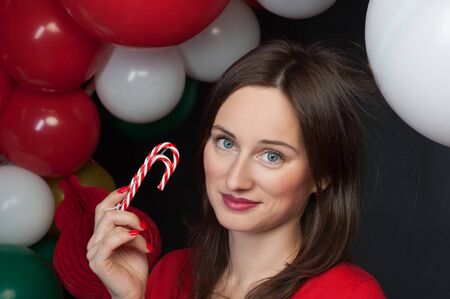Woman with Christmas candy with balloons on background