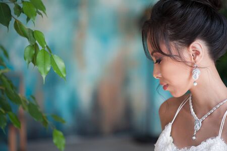 Portrait of asian bride in white dress near plant at roomの写真素材