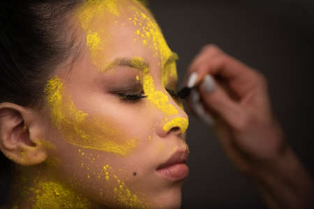 Portrait of asian woman with yellow powder paint on her faceの写真素材