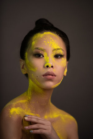Portrait of asian woman with yellow powder paint on her faceの写真素材