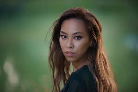 Portrait of young candid asian woman at park with blurred background