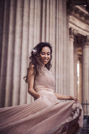 Young asian beautiful woman in dress near columns outdoorsの写真素材