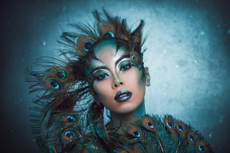 Portrait of woman with creative makeup. Peacock feathers on the faceの写真素材