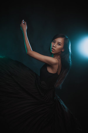 Young asian woman in black dress at motion in studioの写真素材